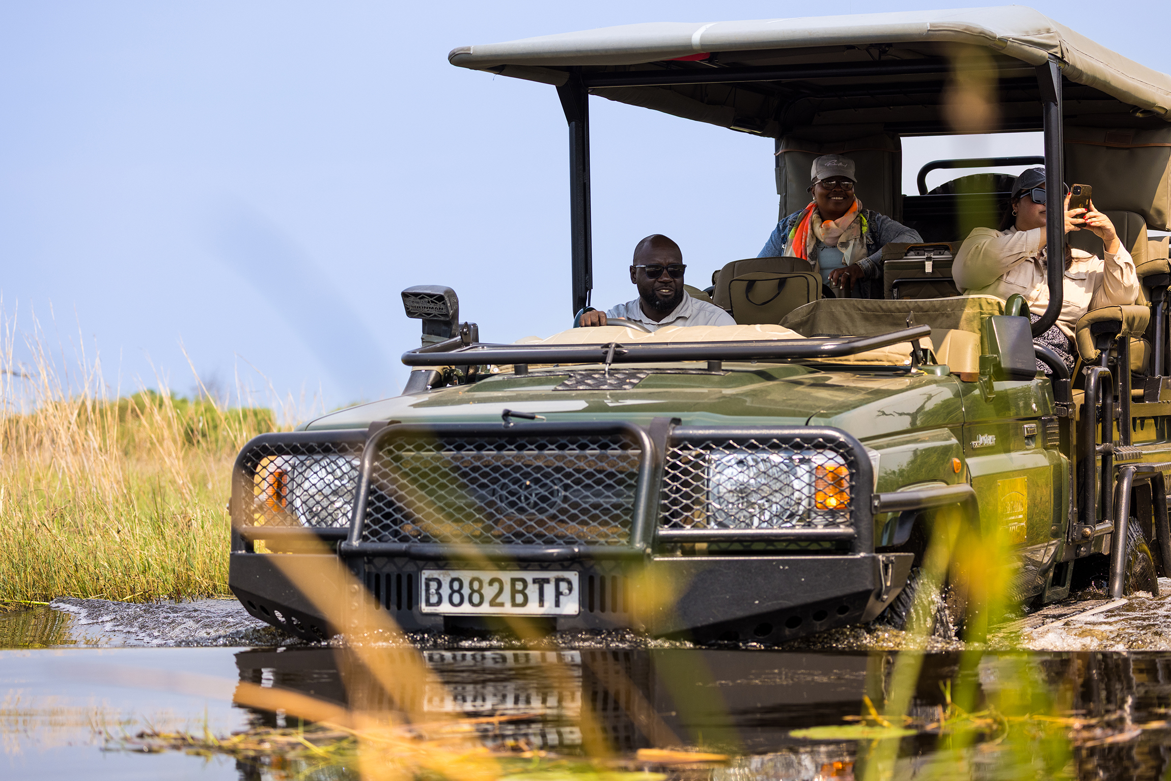 Great plains conservation duba plains camp guest in water with guide in safari vehicle