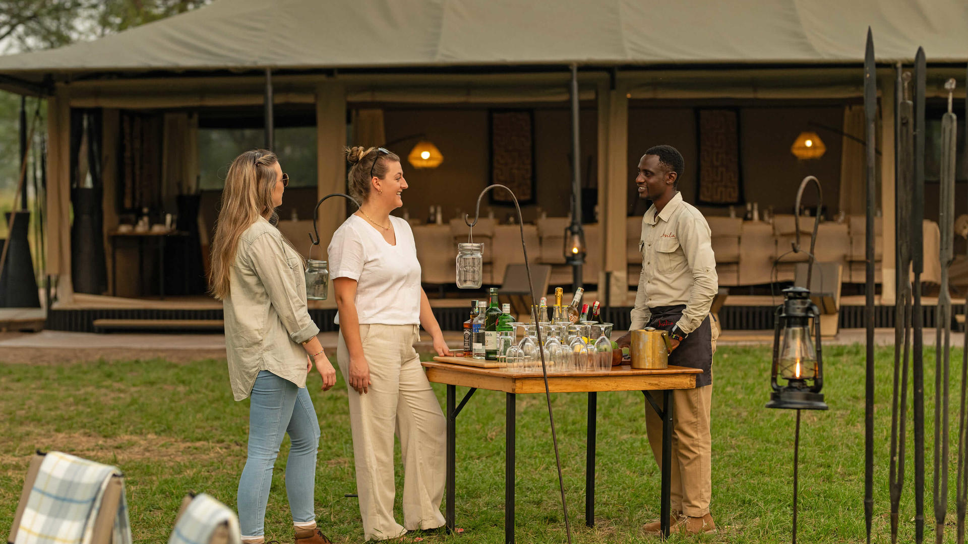 Asilia africa ubuntu migration camp guests ordering drinks at sundowners