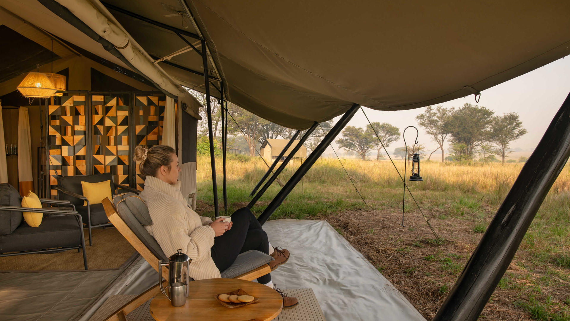 Asilia africa ubuntu migration camp guest enjoying a morning coffee outside their tent