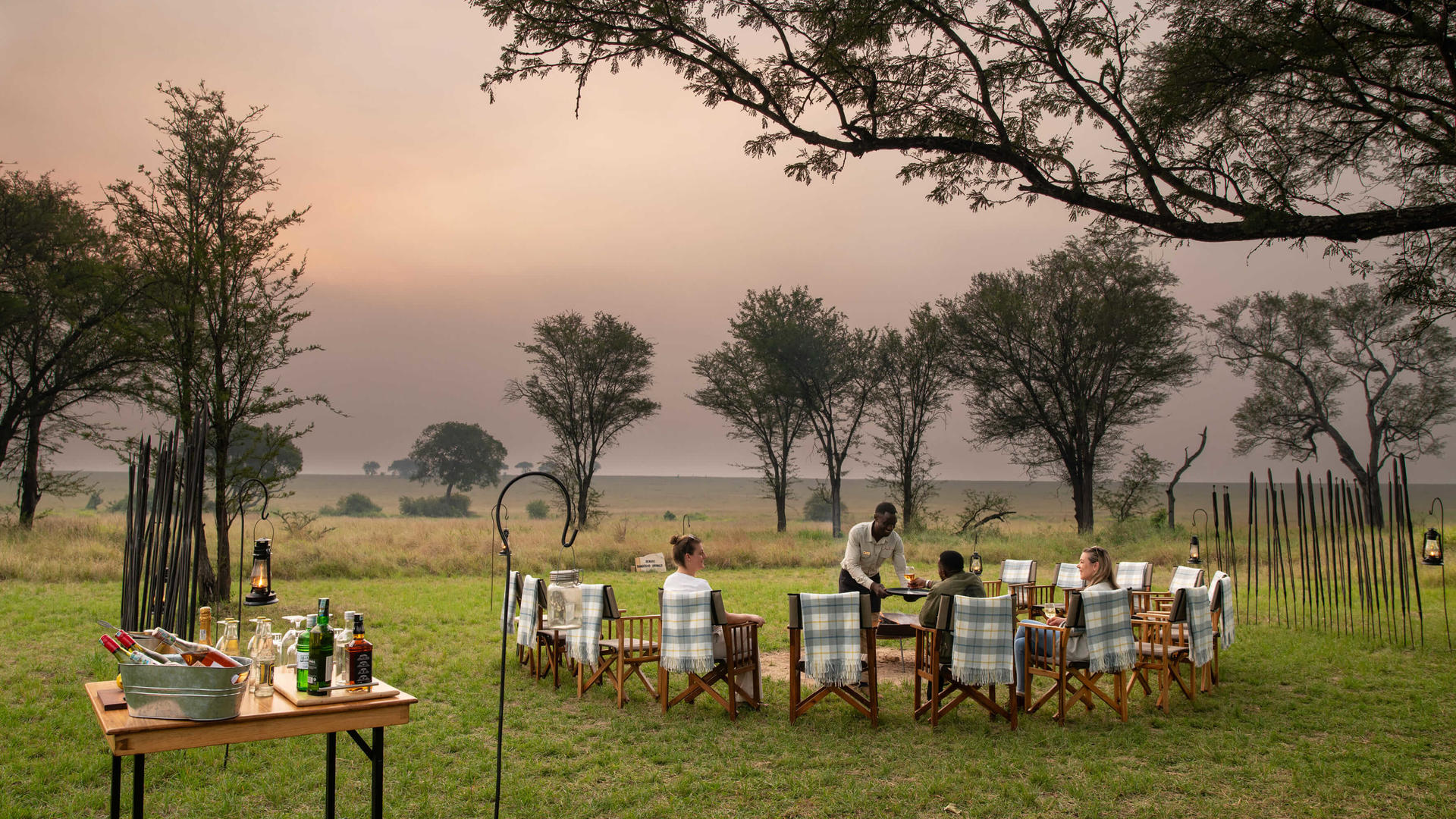 Asilia africa ubuntu migration camp guests enjoying sundowners